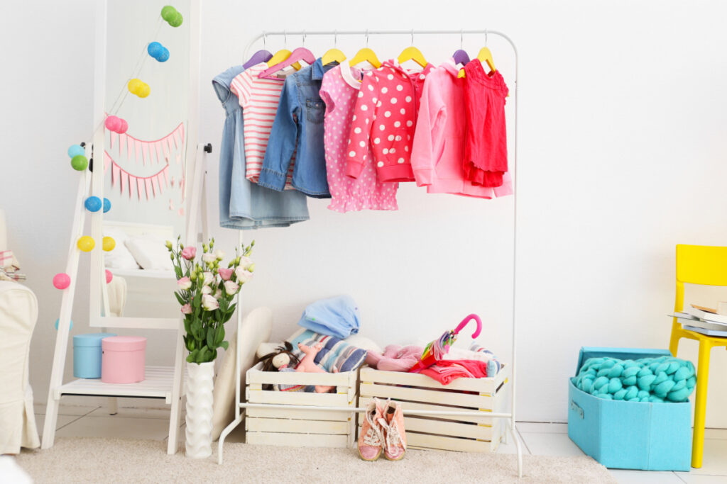 rolling wardrobe rack with colorful baby clothes on it