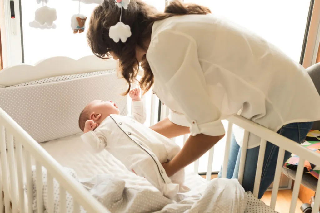 mom putting baby to sleep, hoping to avoid diaper leaks at night