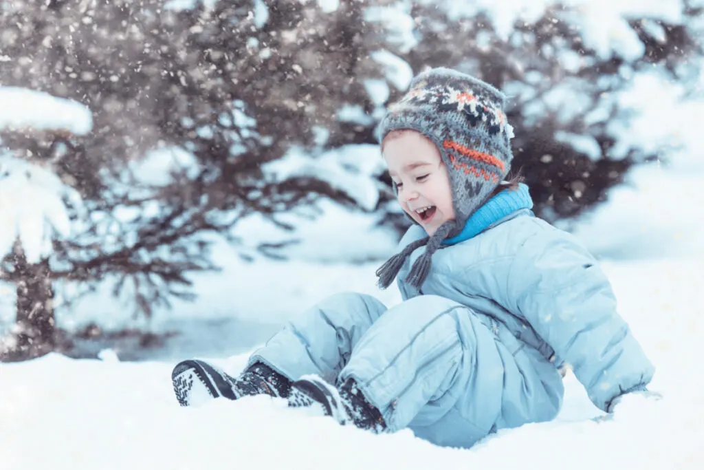 happy one-year-old playing outside in the snow