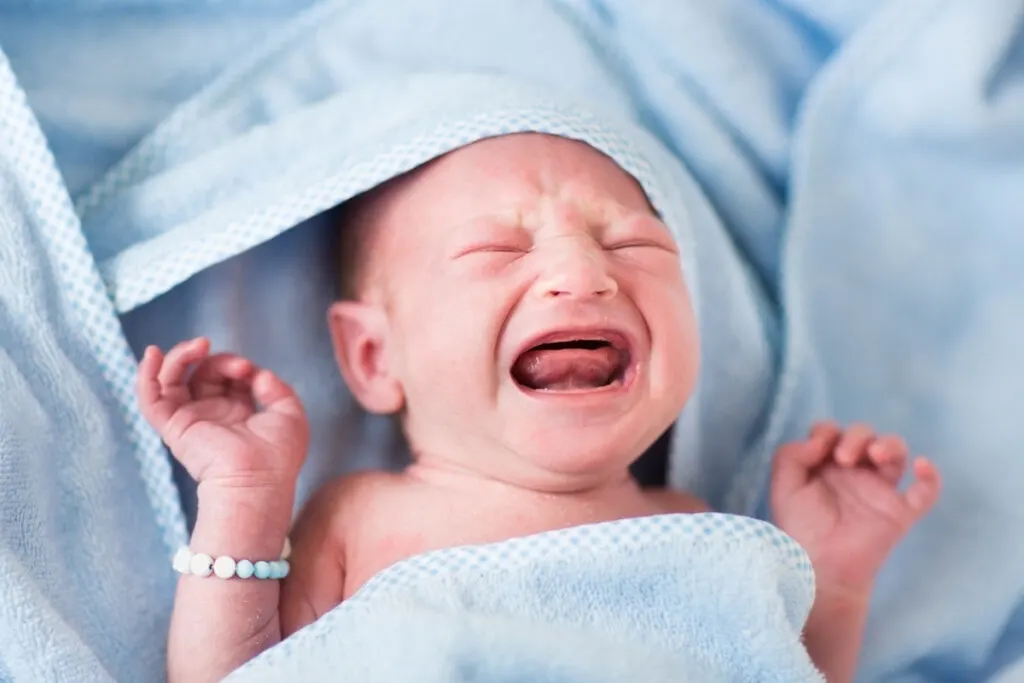 baby wrapped in bath towels, crying after bath time