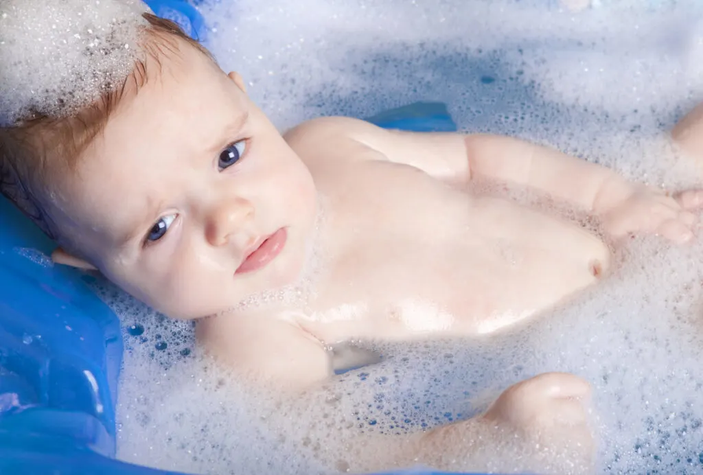 young baby in bath, not happy 