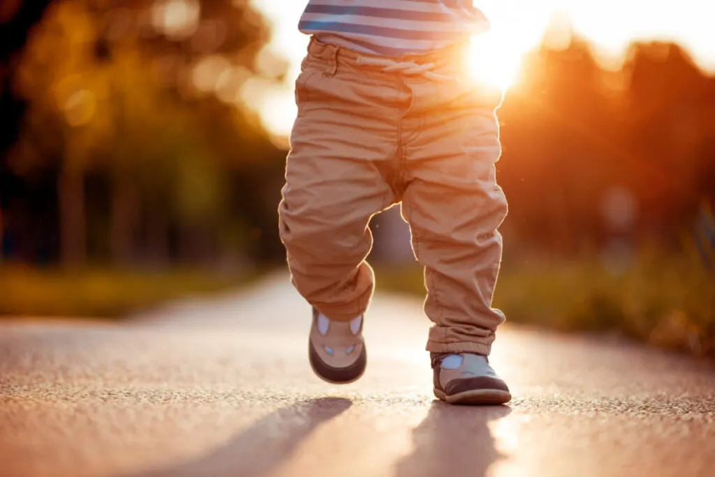 baby boy with mysterious name walking on road in comfy shoes
