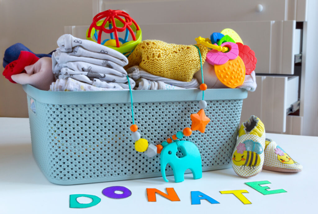 plastic container with baby stuff to give away or donate, word "donate" spelled in colorful letters 