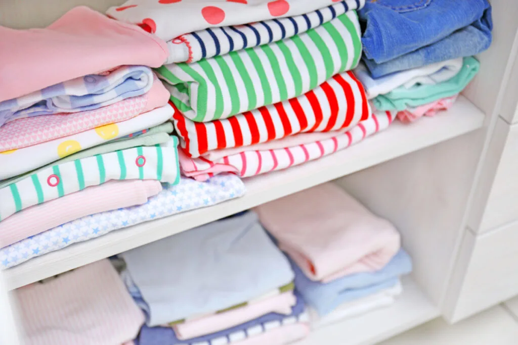 baby clothes stacked and stored neatly on shelf in closet