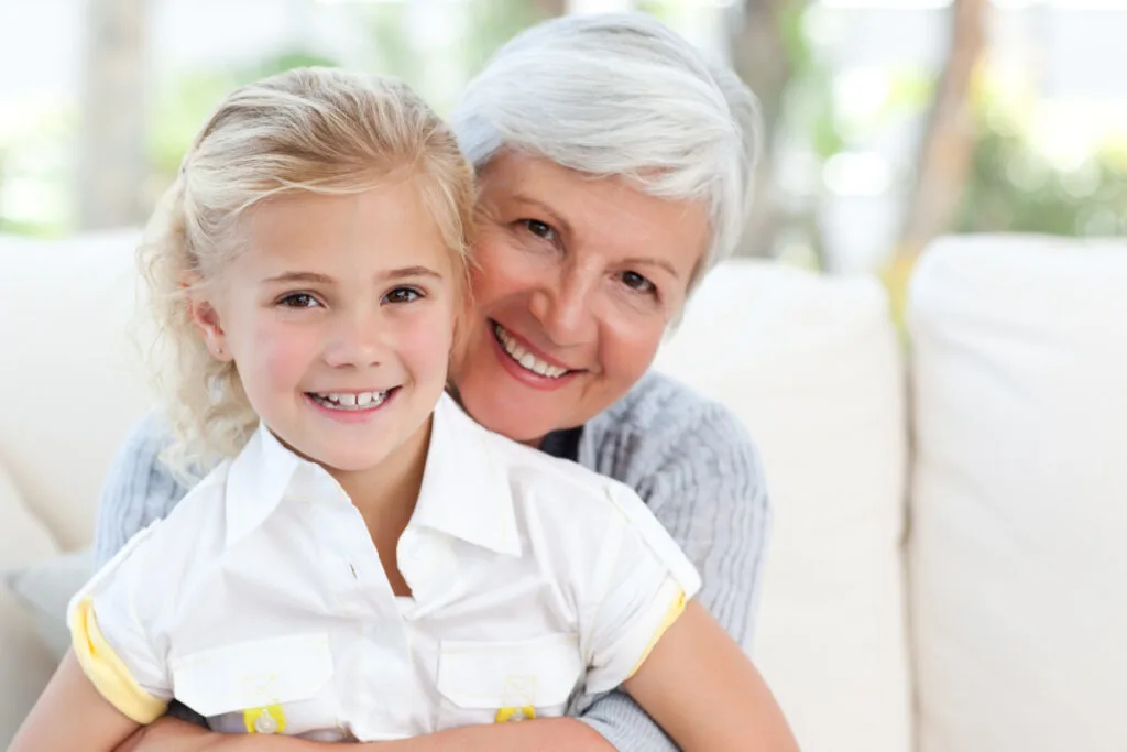 smiling, over involved grandmother hugging happy grandchild