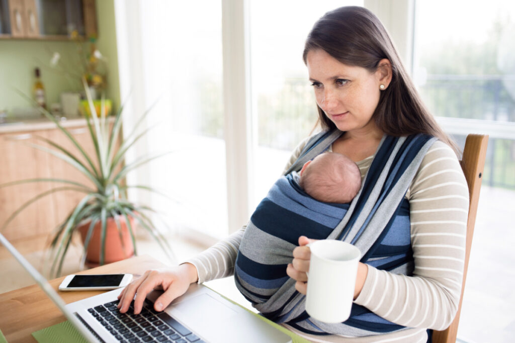mom wearing her baby getting things done on computer