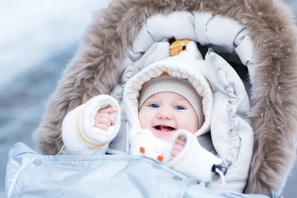 baby bundled up in winter clothing essentials while traveling to a cold climate.