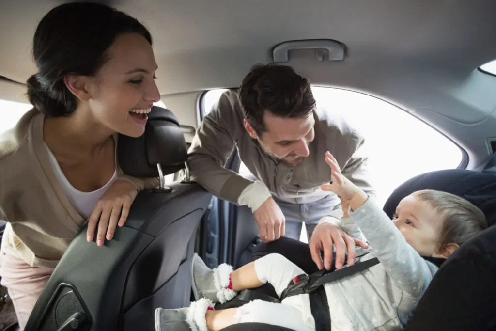 laid back parents putting infant in car seat, getting ready for a long trip.