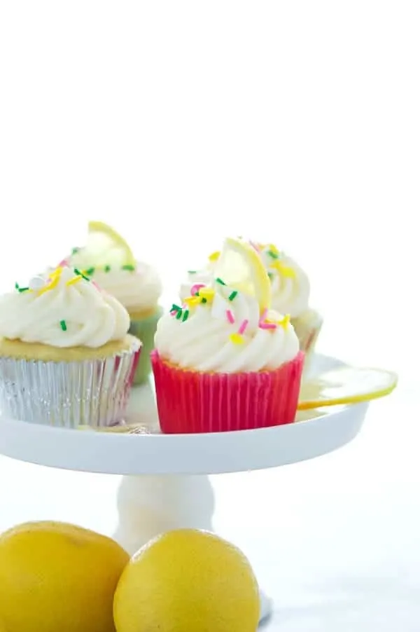 gluten free lemon cupcakes on a cake stand with lemons at the base.