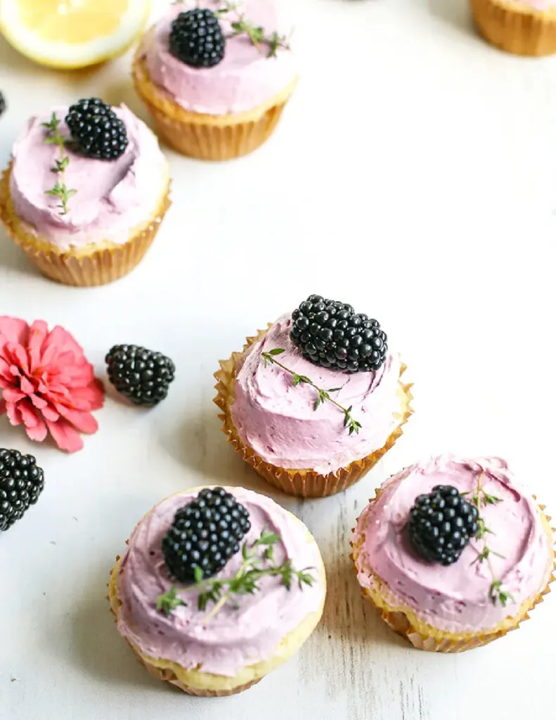lemon blackberry cupcakes with purple frosting and a blackberry on top.