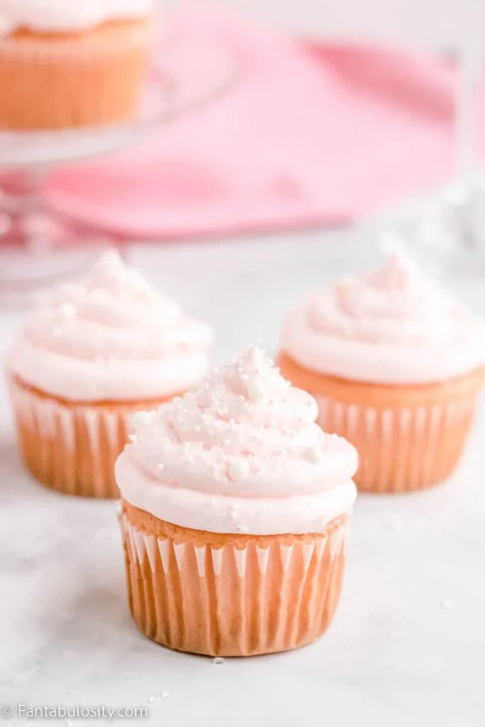 pink champagne cupcakes with gold and white sparkling sugar on top.