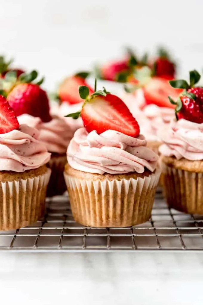 fresh strawberry cupcakes with fresh strawberry frosting and halved strawberries on top. 