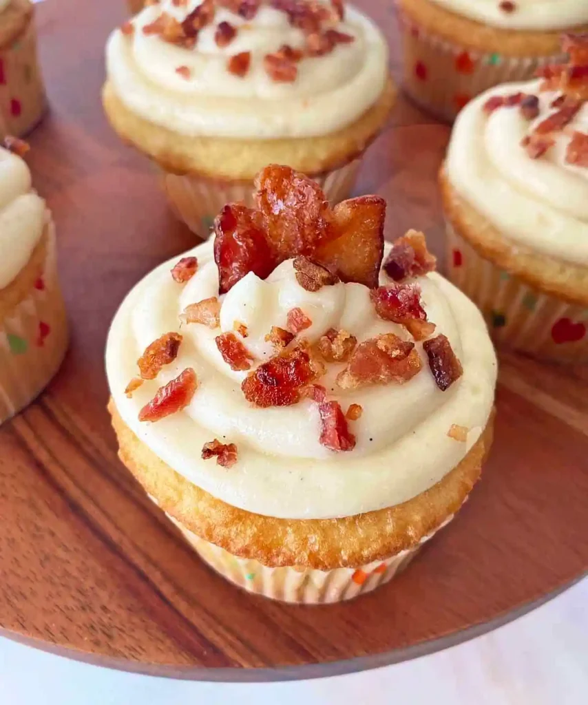 maple bacon cupcakes with crumbled bacon on top.