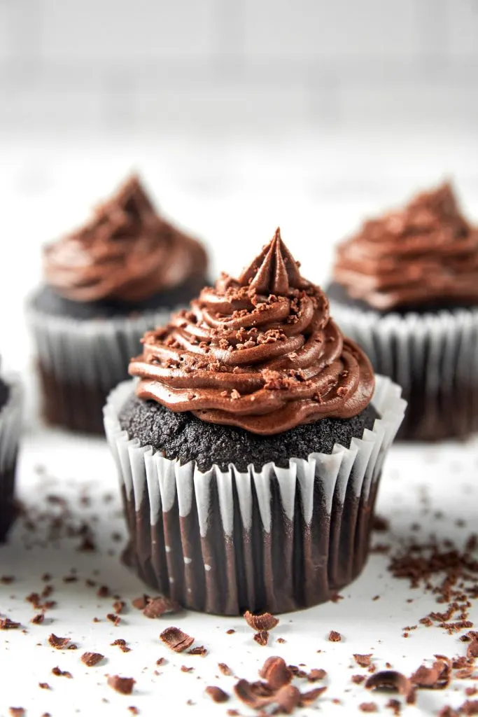 vegan chocolate cupcakes surrounded by chocolate shavings. 