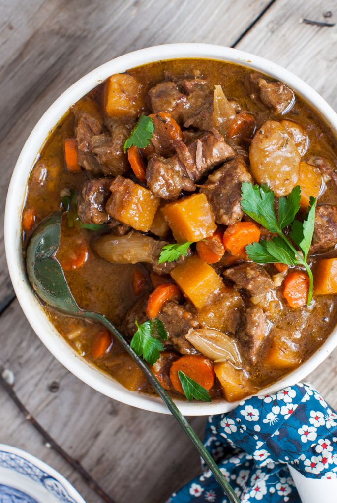 beef stew with root vegetables in bowl with colorful napkin nearby.