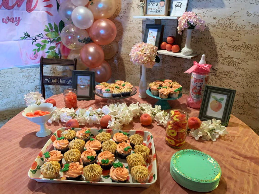 baby shower display table with peach ring candy and homemade cupcakes to save money.