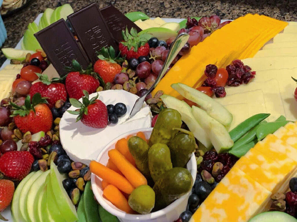 cheese and veggie tray with dips and pickles and chocolate.