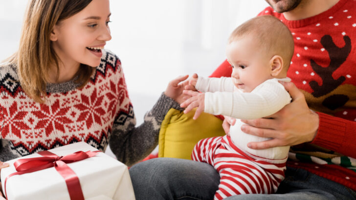 baby home for Christmas with parents, reaching for present.