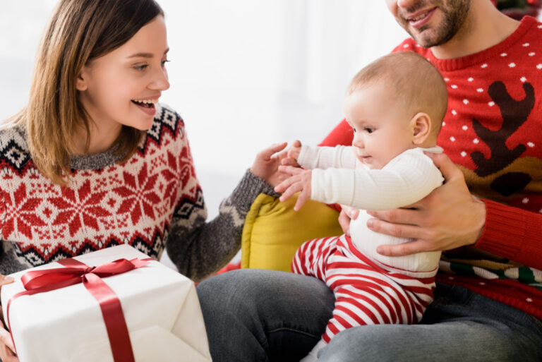 baby home for Christmas with parents, reaching for present.