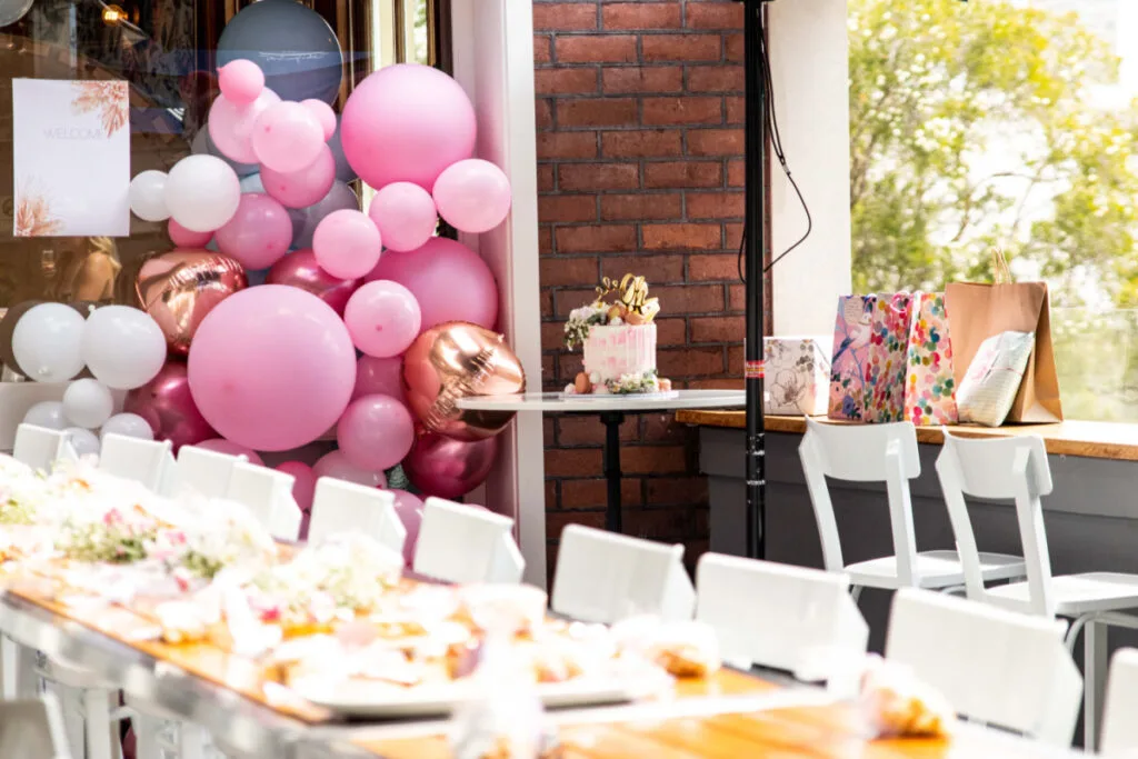 baby shower venue with beautifully set tables and pink and white balloon arch.