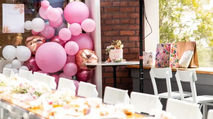 baby shower venue with beautifully set tables and pink and white balloon arch.