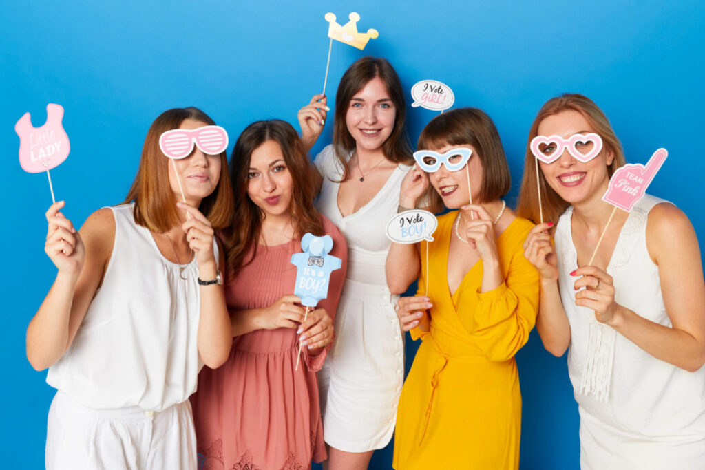 friends at a baby shower with signs with their baby gender guess.
