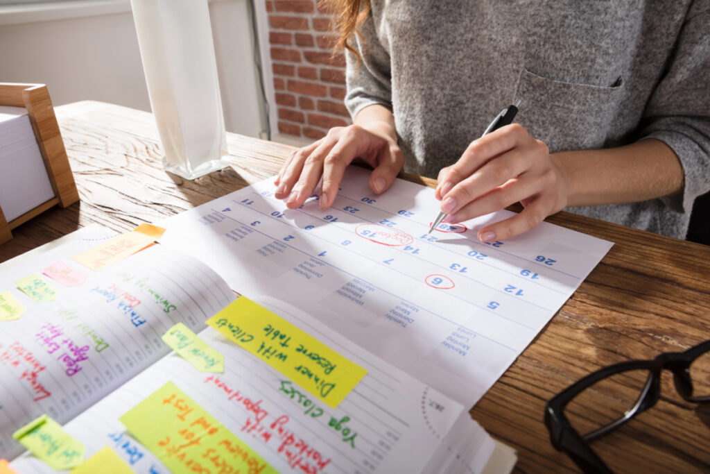 baby shower planner looking at large desk calendar to choose the best date for the shower.