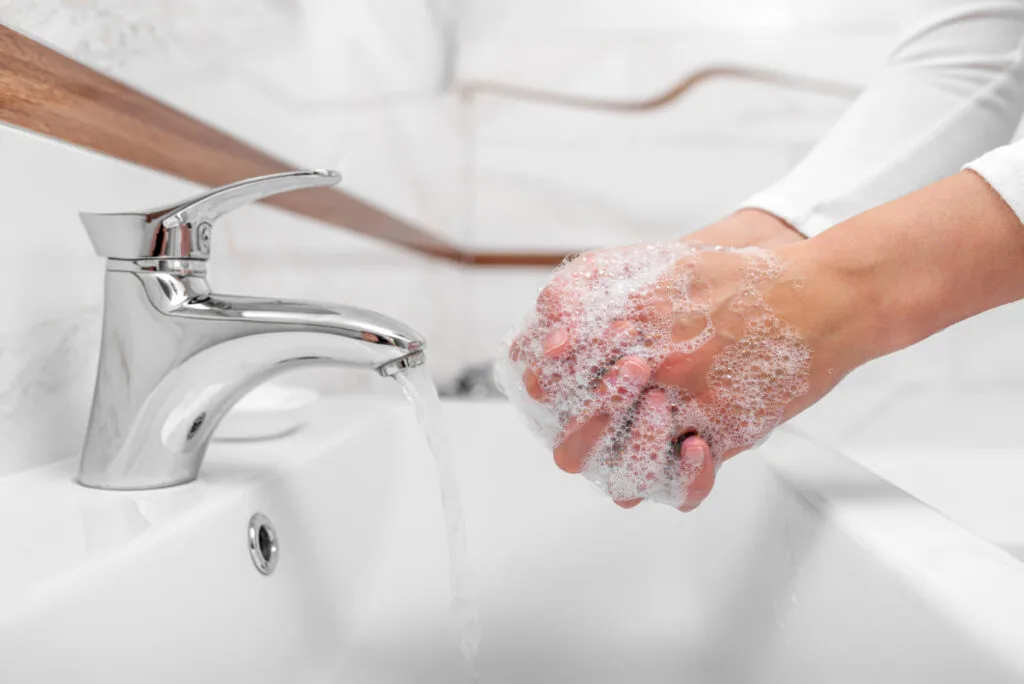 Someone washing hands to prepare for newborn visit.