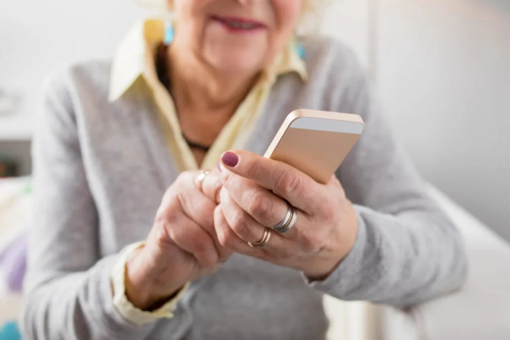 grandma holding phone, sharing newborn photos on social media.