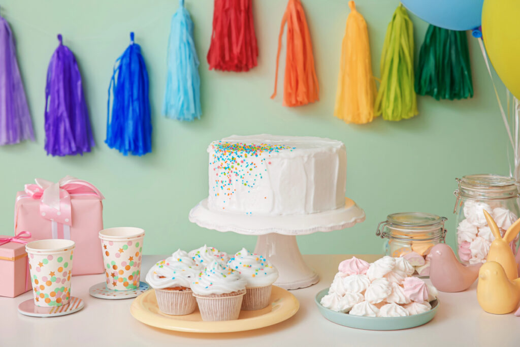 baby shower dessert table with cake and treats and rainbow decor.