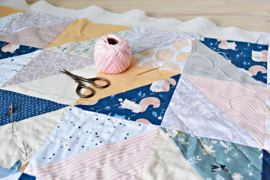 baby shower quilt in process with scissors and thread on top.