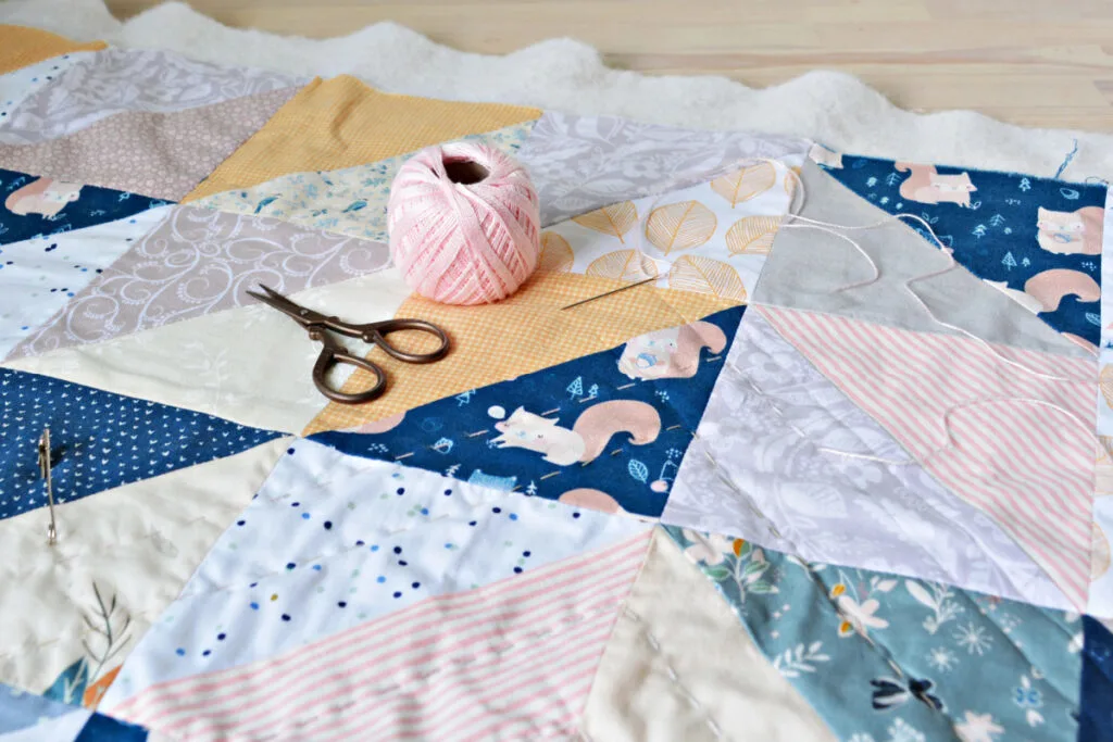 baby shower quilt in process with scissors and thread on top.