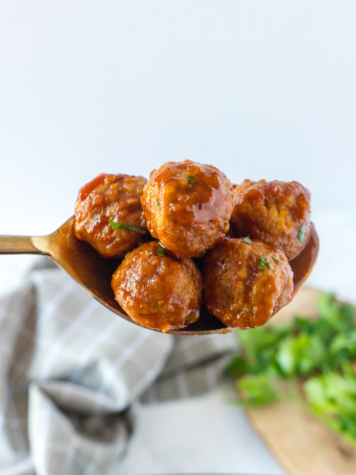 cranberry BBQ meatballs on golden spoon, ready to serve at baby shower.