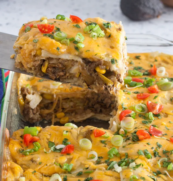layered enchilada casserole with slice being lifted out to serve.