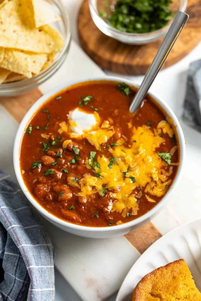 bowl of instant pot turkey chili with spoon, tortilla chips and chopped cilantro in background.