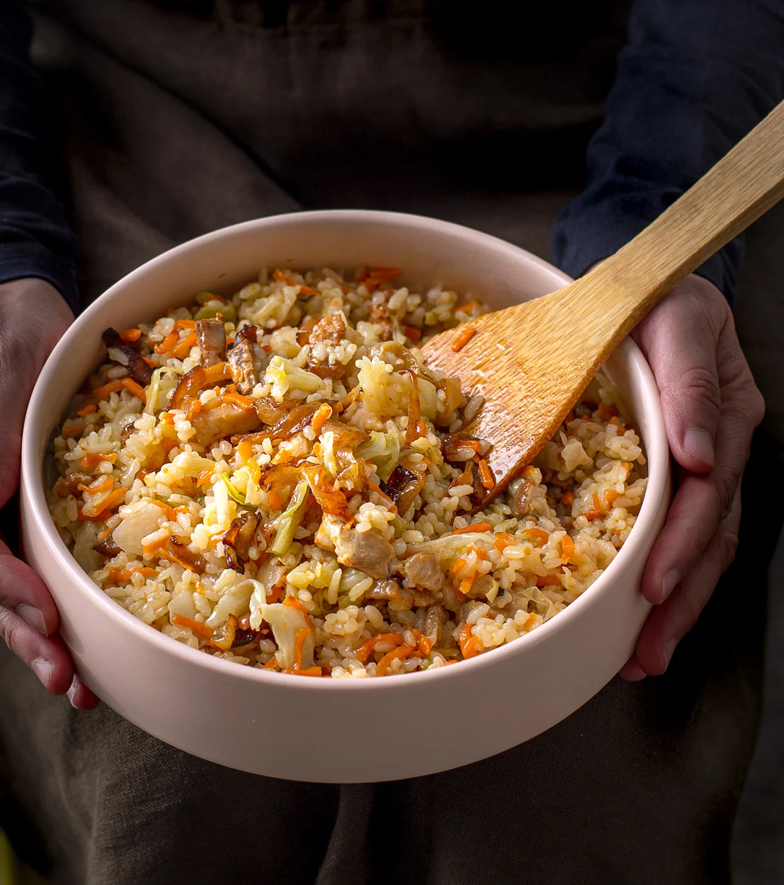 pink bowl filled with a serving of one pot rice with pork and veggies.