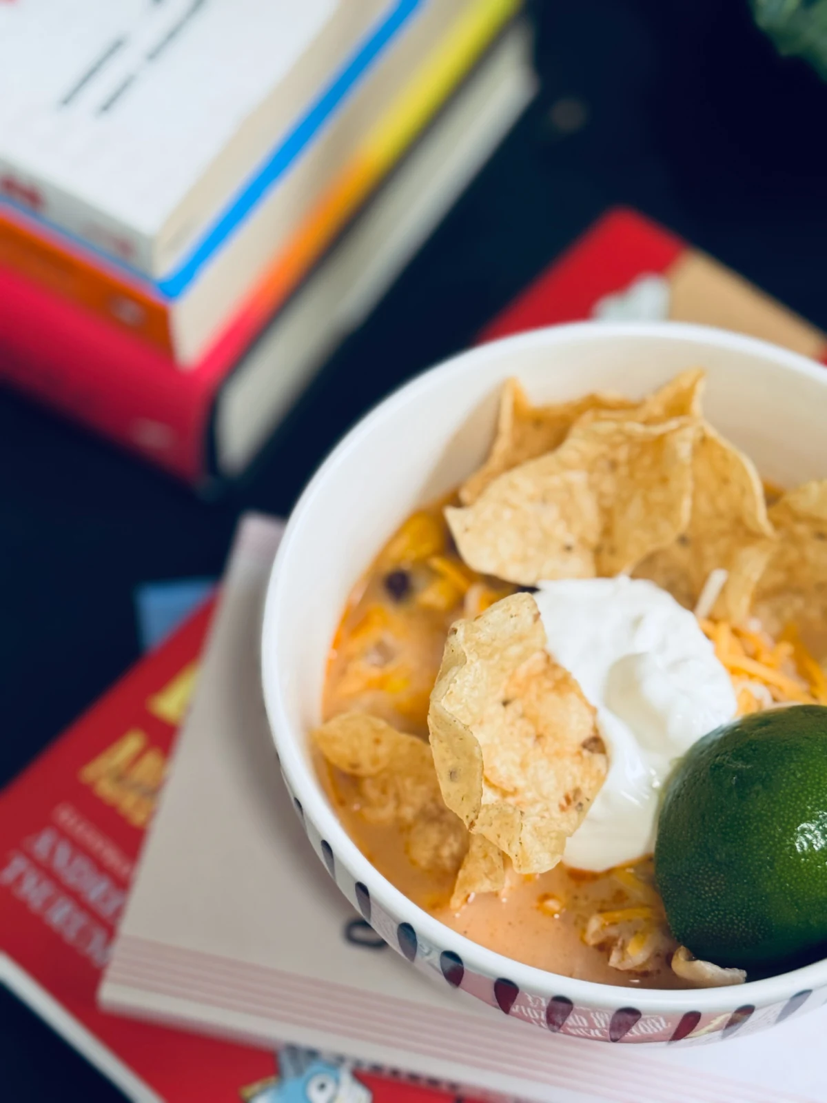 chicken tortilla soup in white bowl with sour cream, tortilla chips and lime.