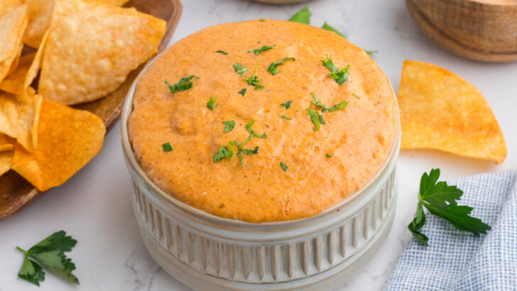 cottage cheese queso dip in large white ramekin with tortilla chips nearby.