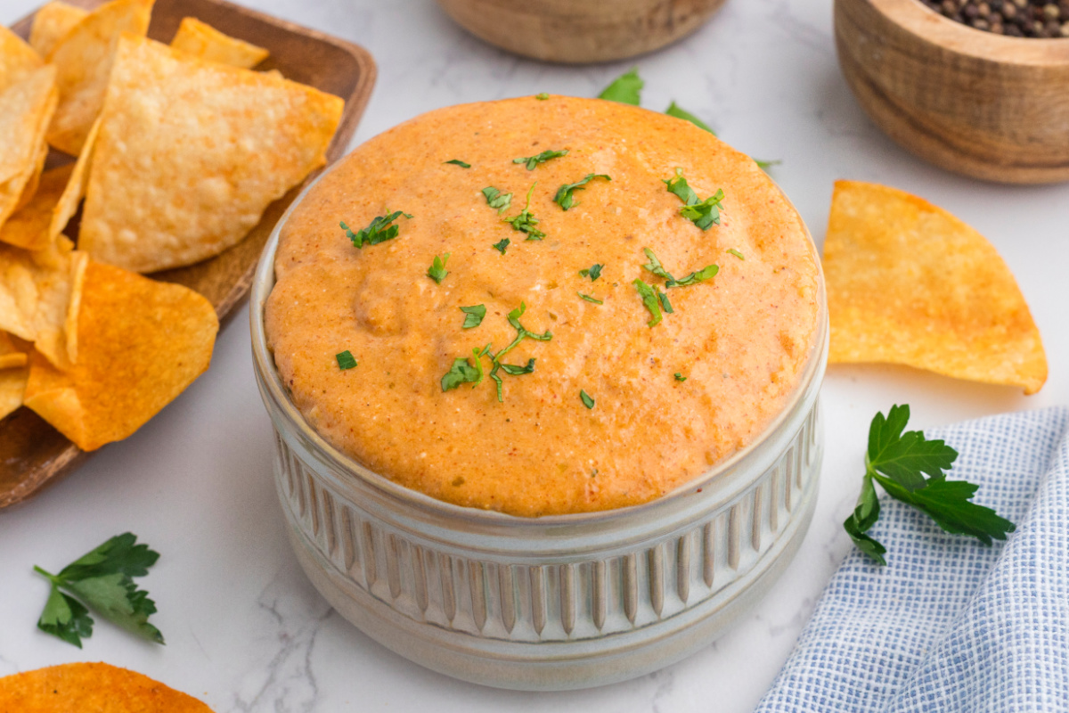 cottage cheese queso dip in large white ramekin with tortilla chips nearby.