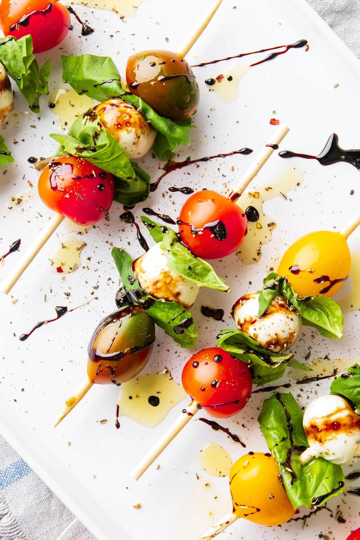 easy caprese skewer appetizer drizzled with balsamic and olive oil on white platter ready for baby shower
