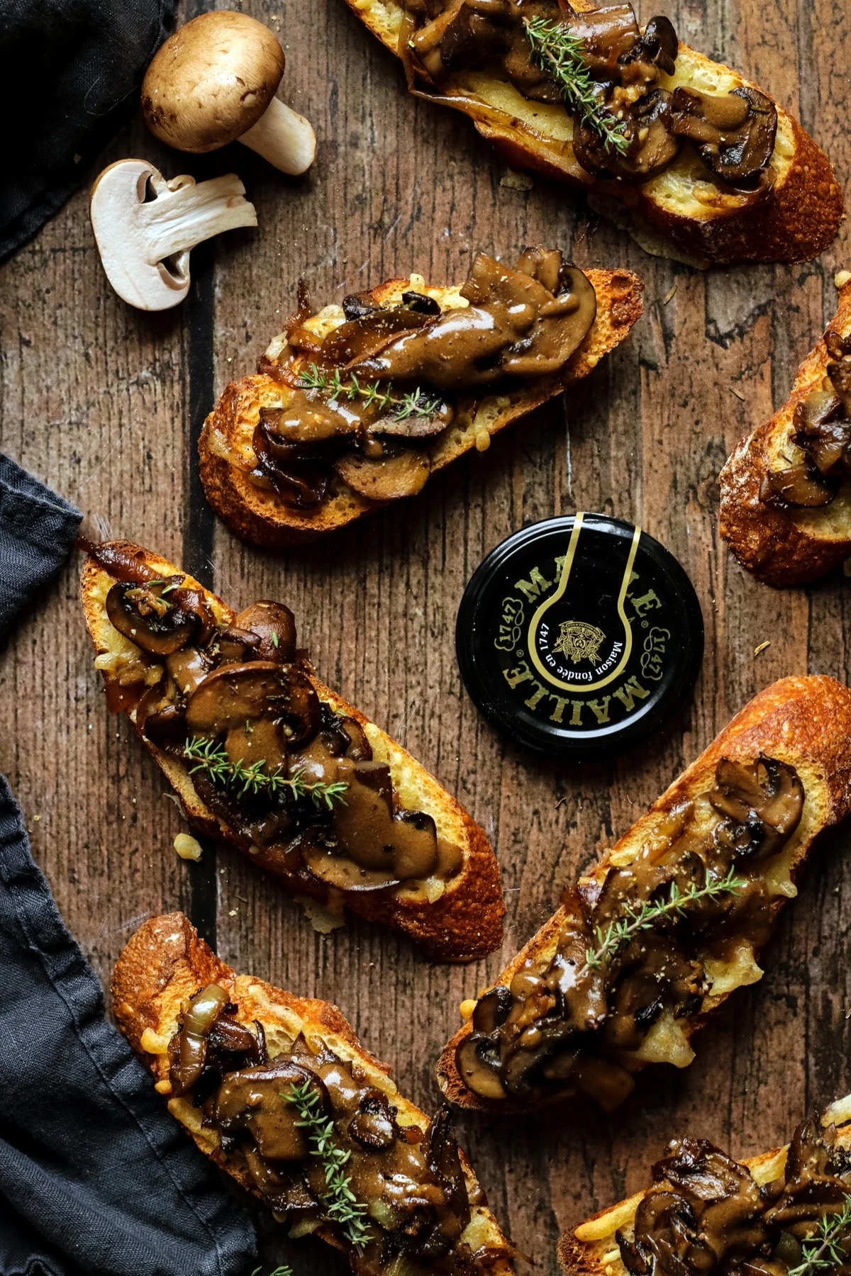 mushroom crostini assembled flat lay on wooden cutting board.