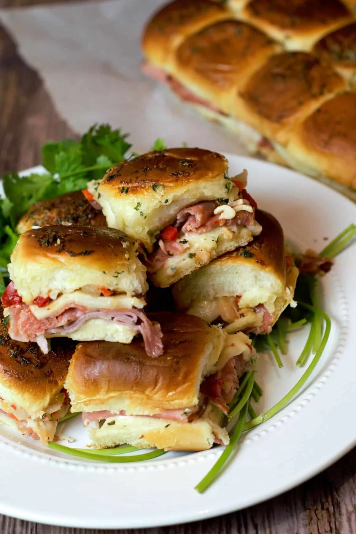 Italian sub sliders on white serving plate on baby shower appetizer table.