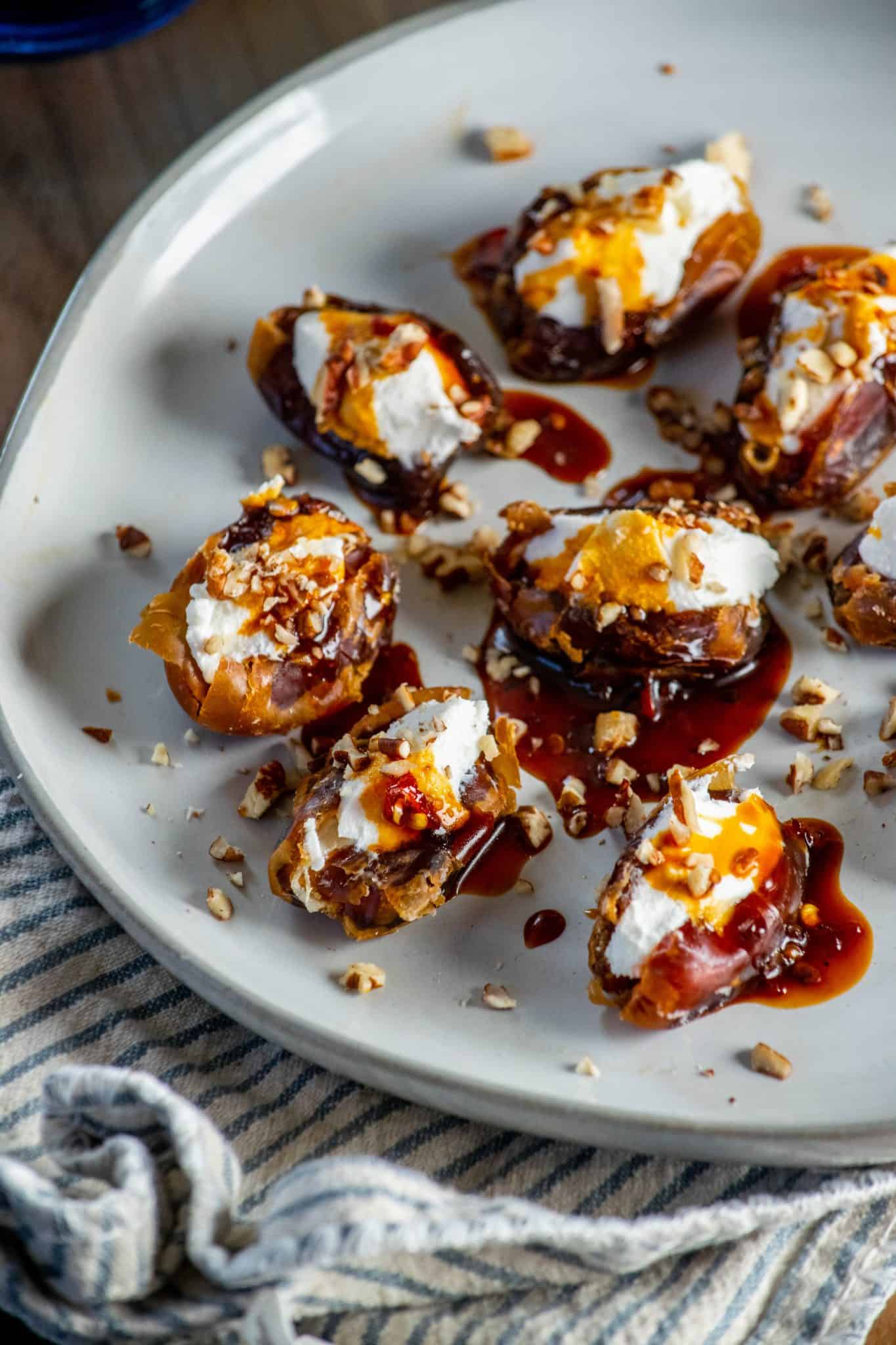 easy goat cheese stuffed dates on pottery plate with striped dish towel in background.