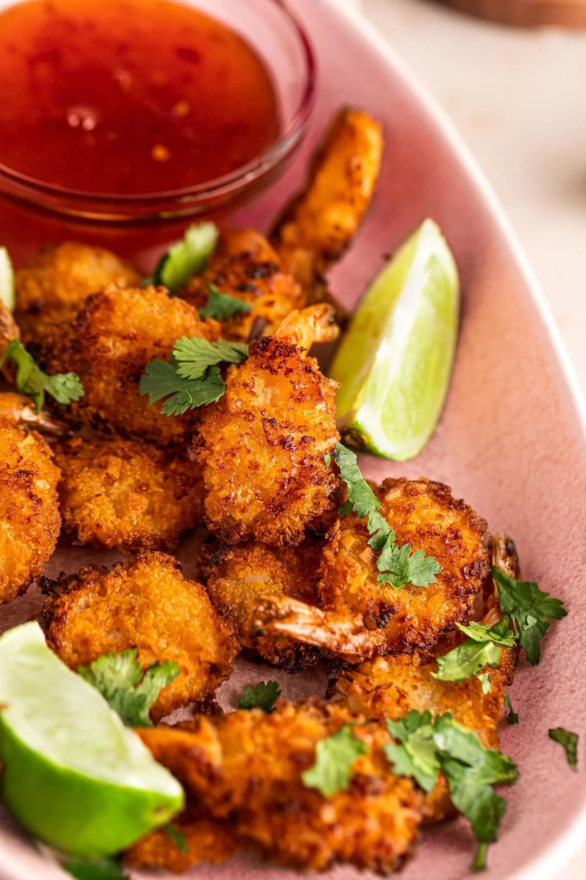 breaded coconut shrimp on plink platter with sauce in background, ready to serve at baby shower.
