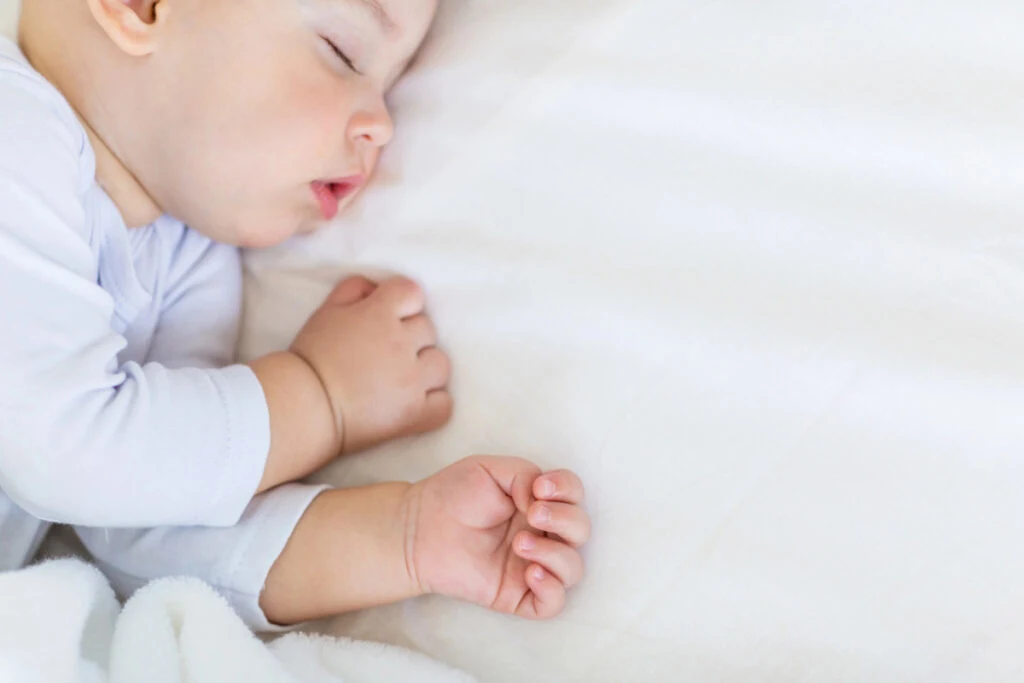 baby napping on white sheets.