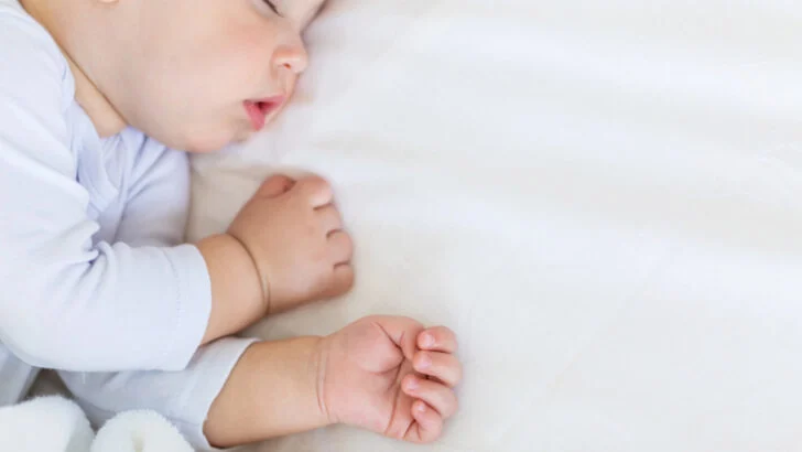 baby napping on white sheets.