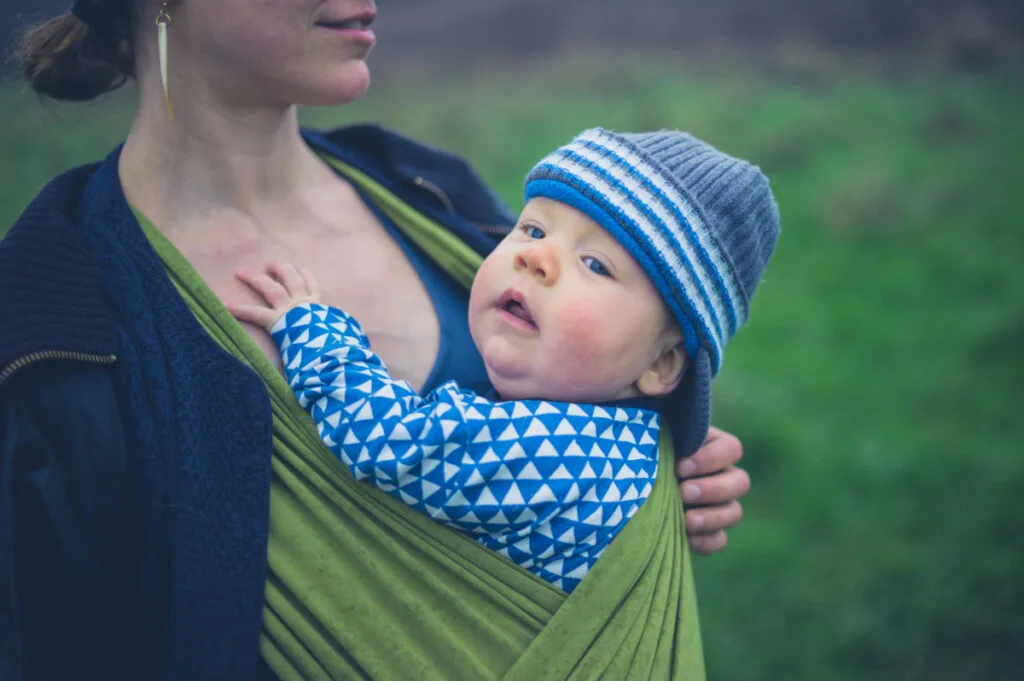 baby who won't nap in green front-facing baby carrier with mom.